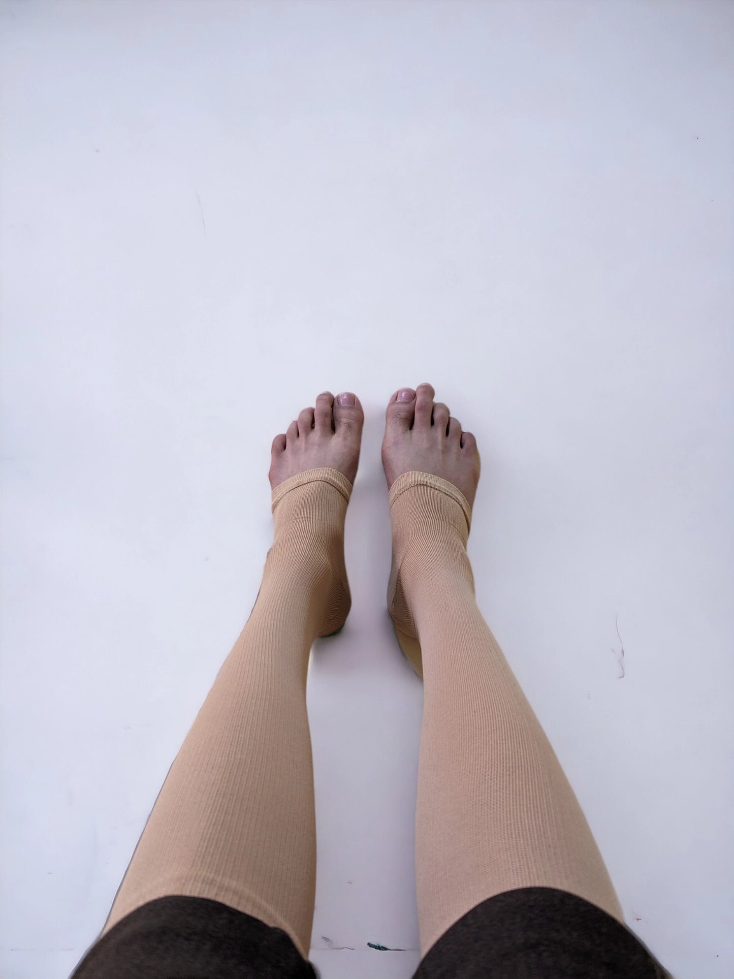 Two legs wearing skin colored zippered compression socks