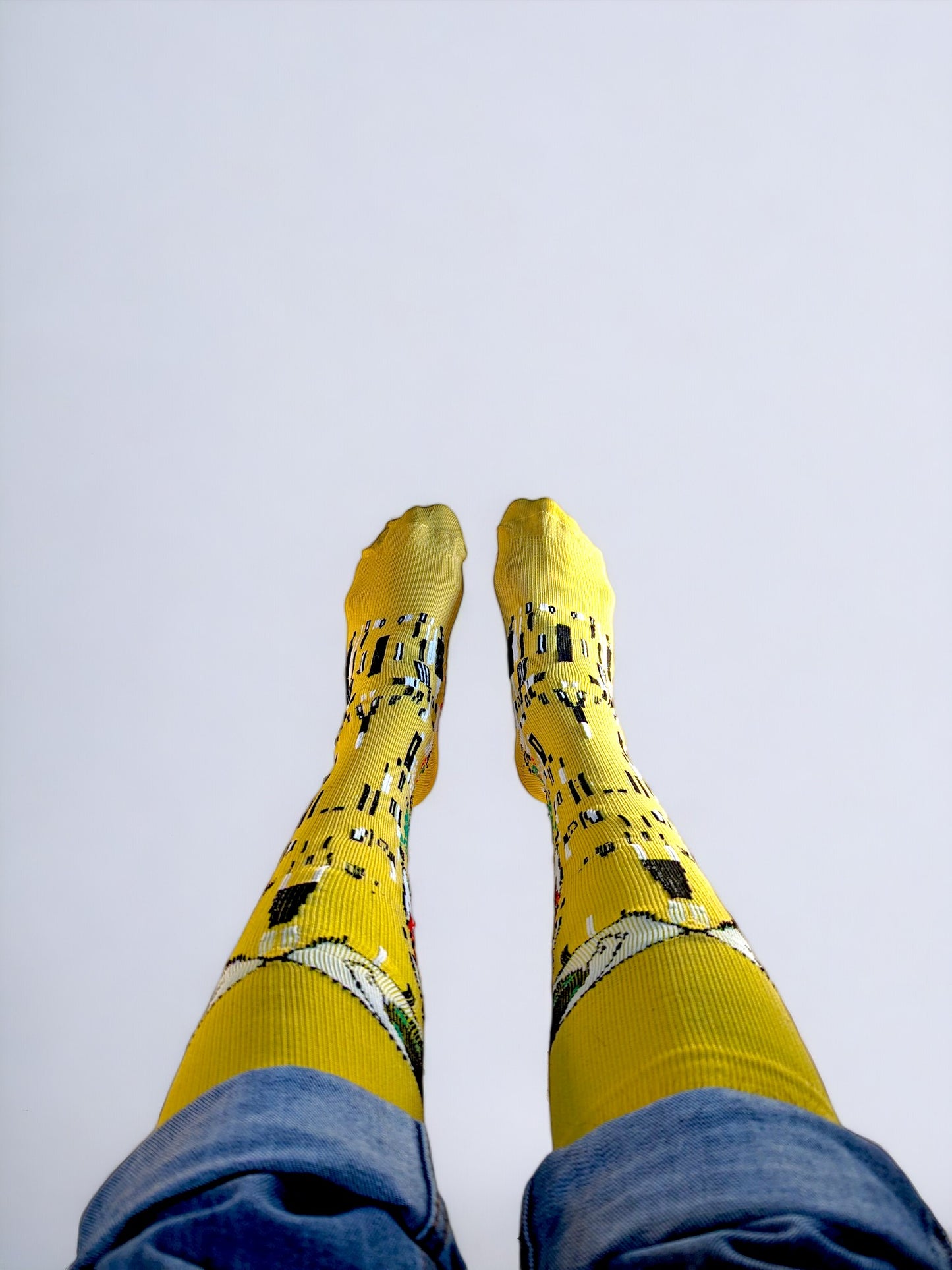 A pair of legs wearing yellow compression socks with the famous painting 'Kiss' printed on it.