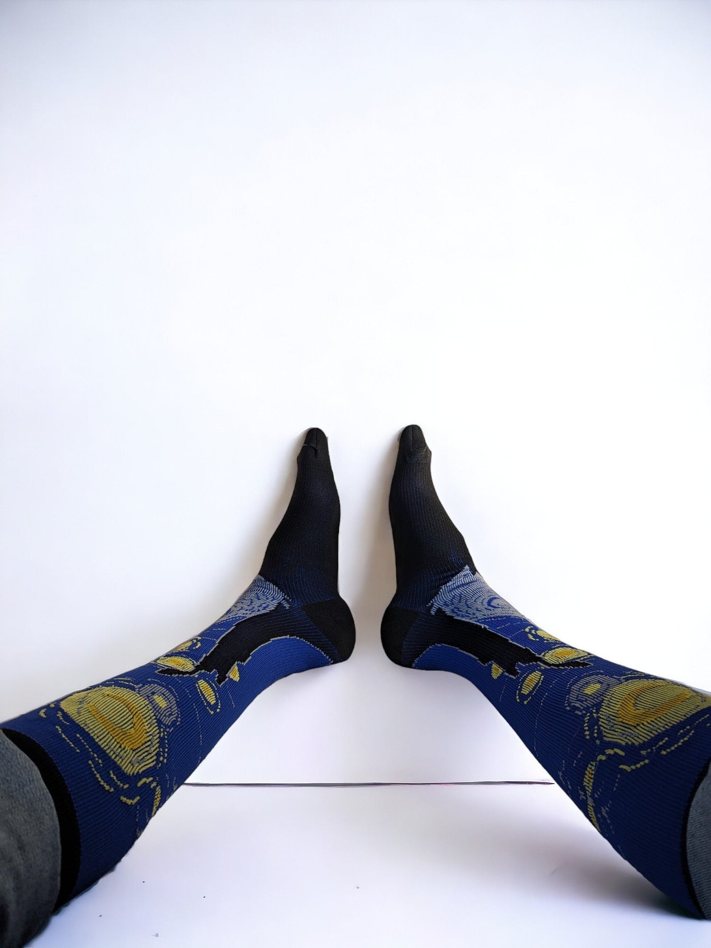 A pair of legs wearing blue compression socks with feet up to the wall