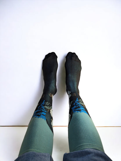 A pair of legs wearing blue compression socks with feet up to the wall