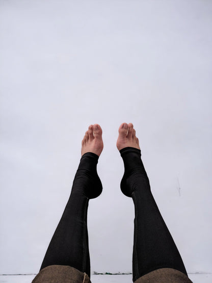 Two legs wearing black colored knee-high zippered compression socks