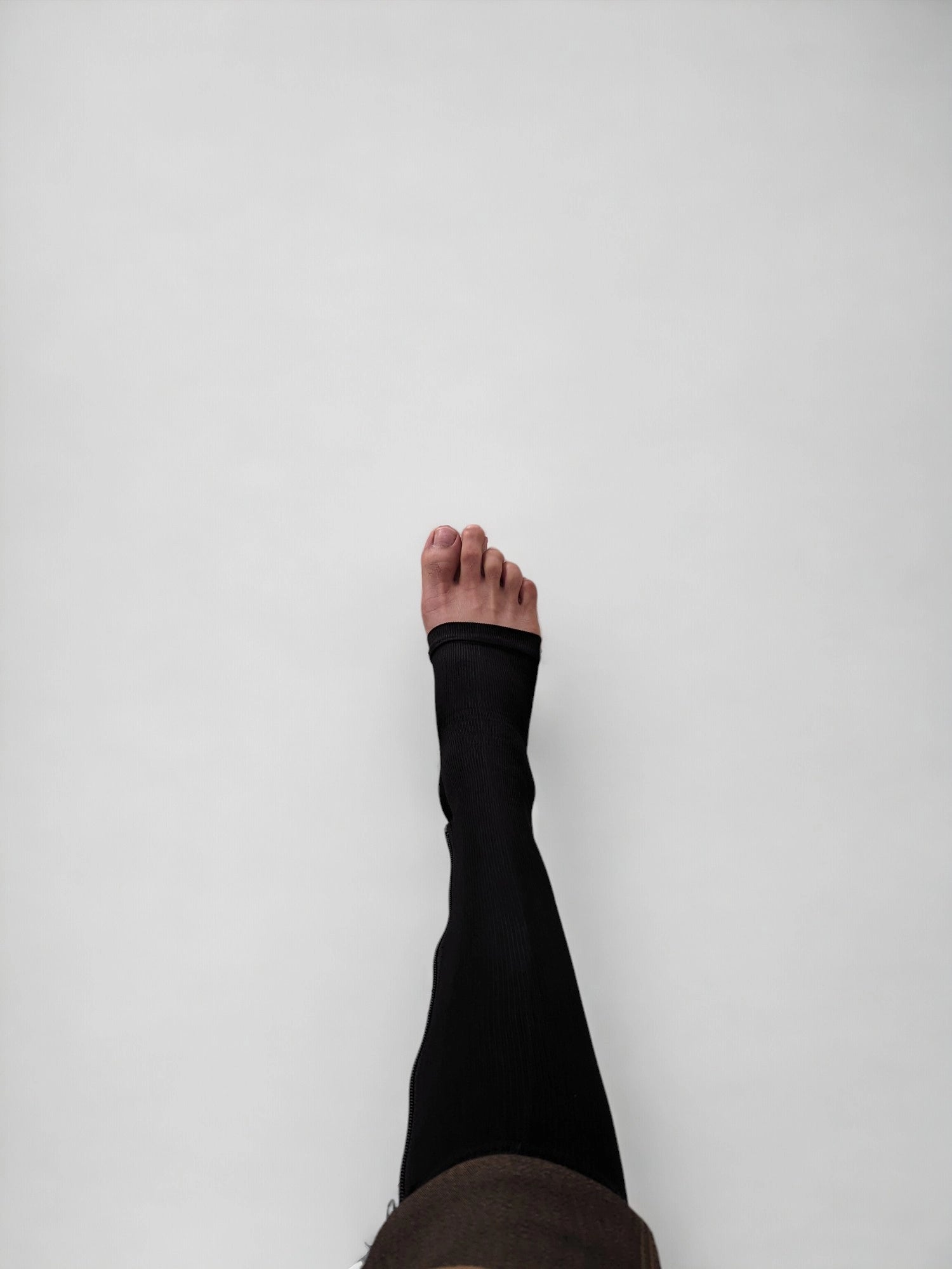 A leg wearing black colored knee-high zippered compression socks