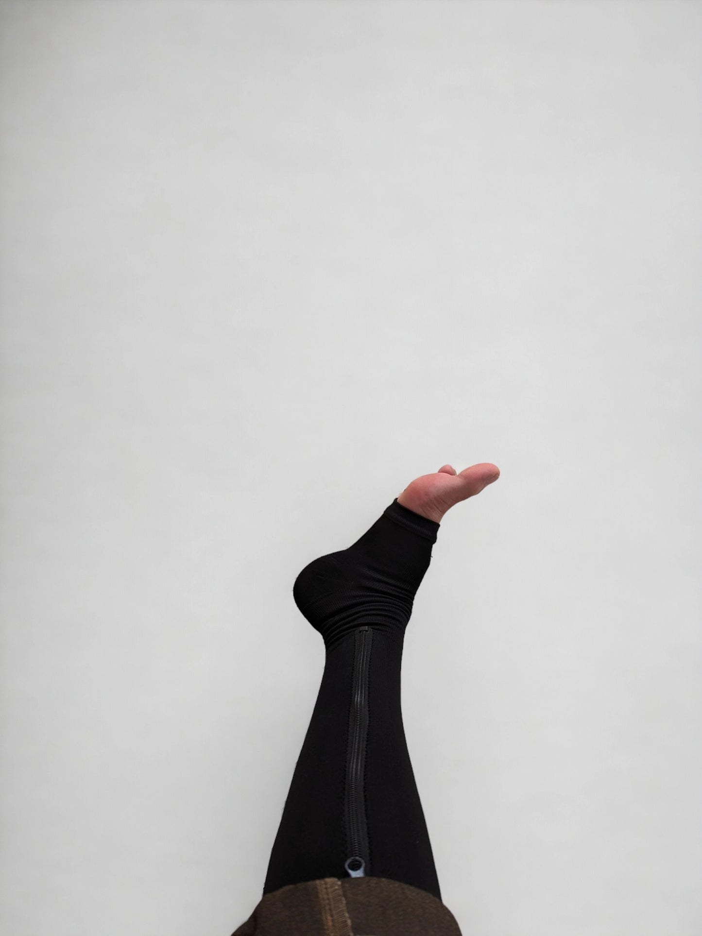 A leg wearing black colored knee-high zippered compression socks