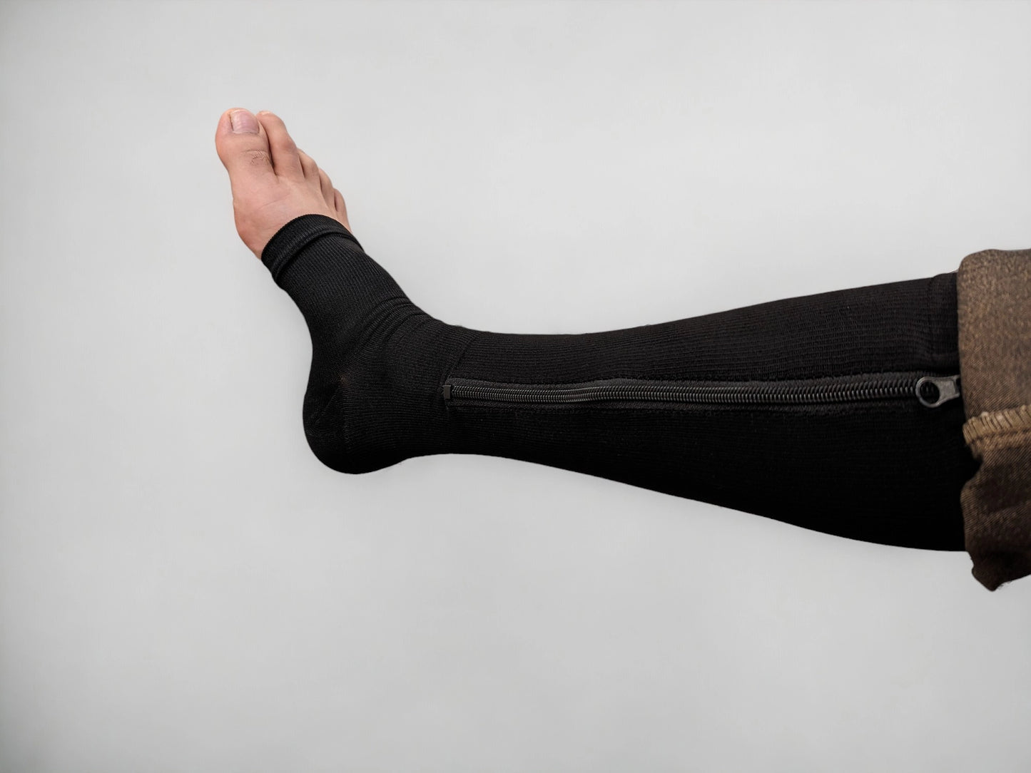 A leg wearing black colored knee-high zippered compression socks