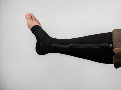 A leg wearing black colored knee-high zippered compression socks