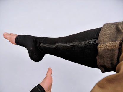Two legs wearing black colored knee-high zippered compression socks