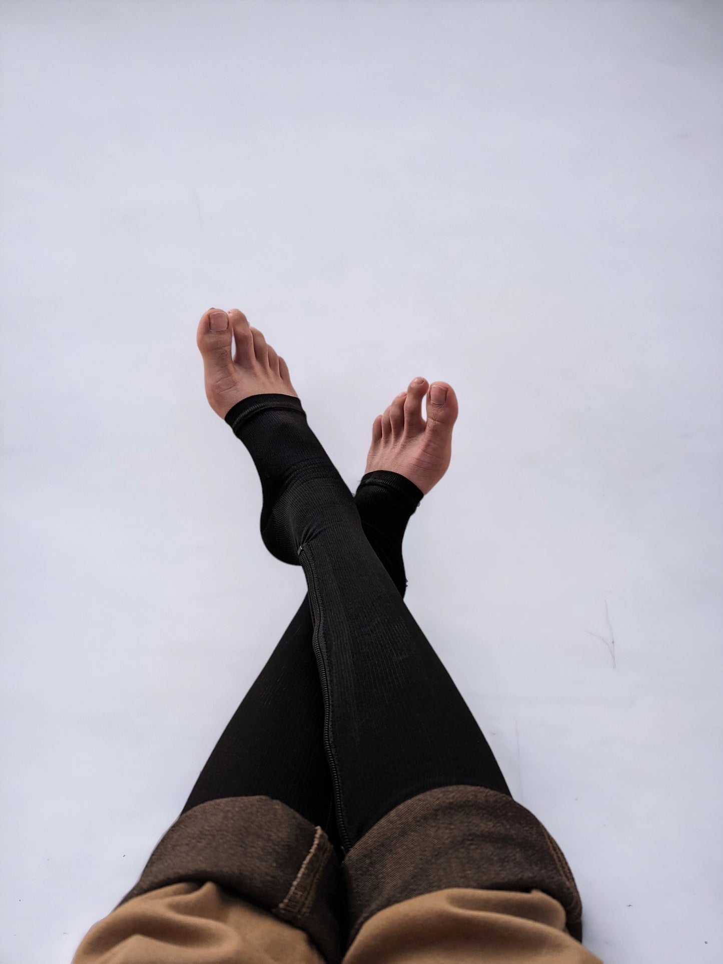 Two legs wearing black colored knee-high zippered compression socks