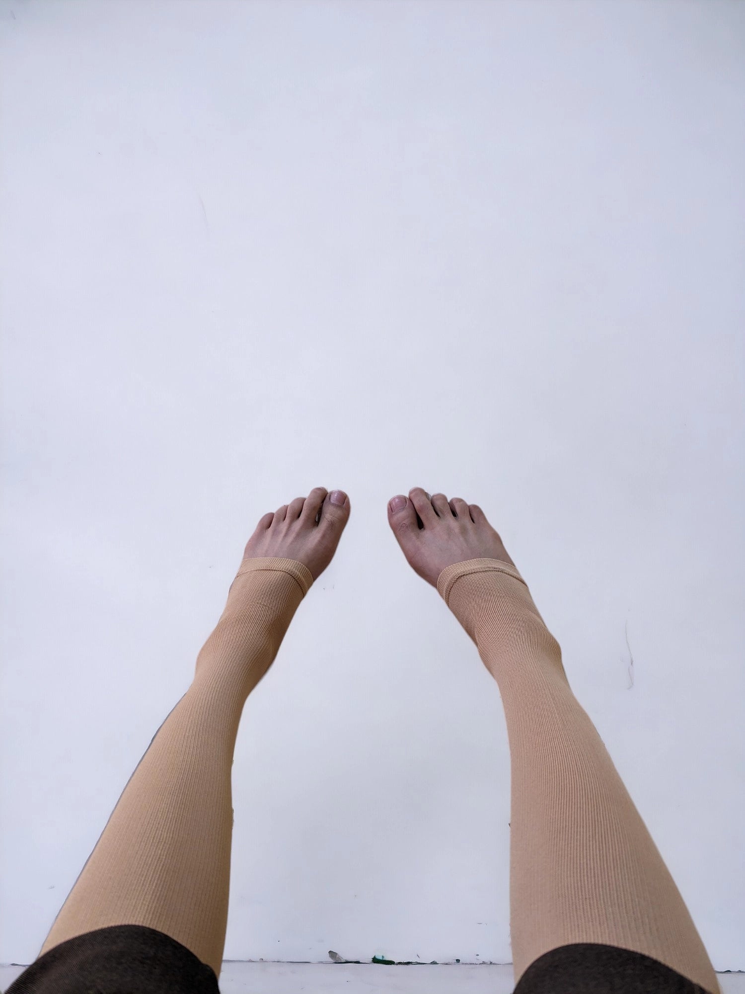 Two legs wearing skin colored knee-high zippered compression socks 