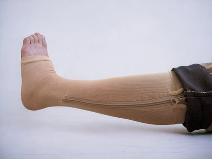 A leg wearing skin-colored knee-high zippered compression socks