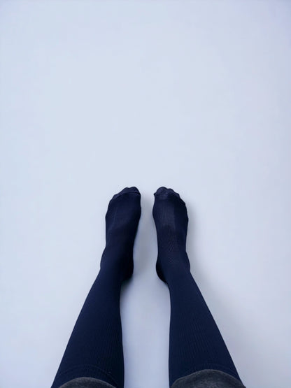 Two legs wearing navy blue graduated compression socks facing upwards.