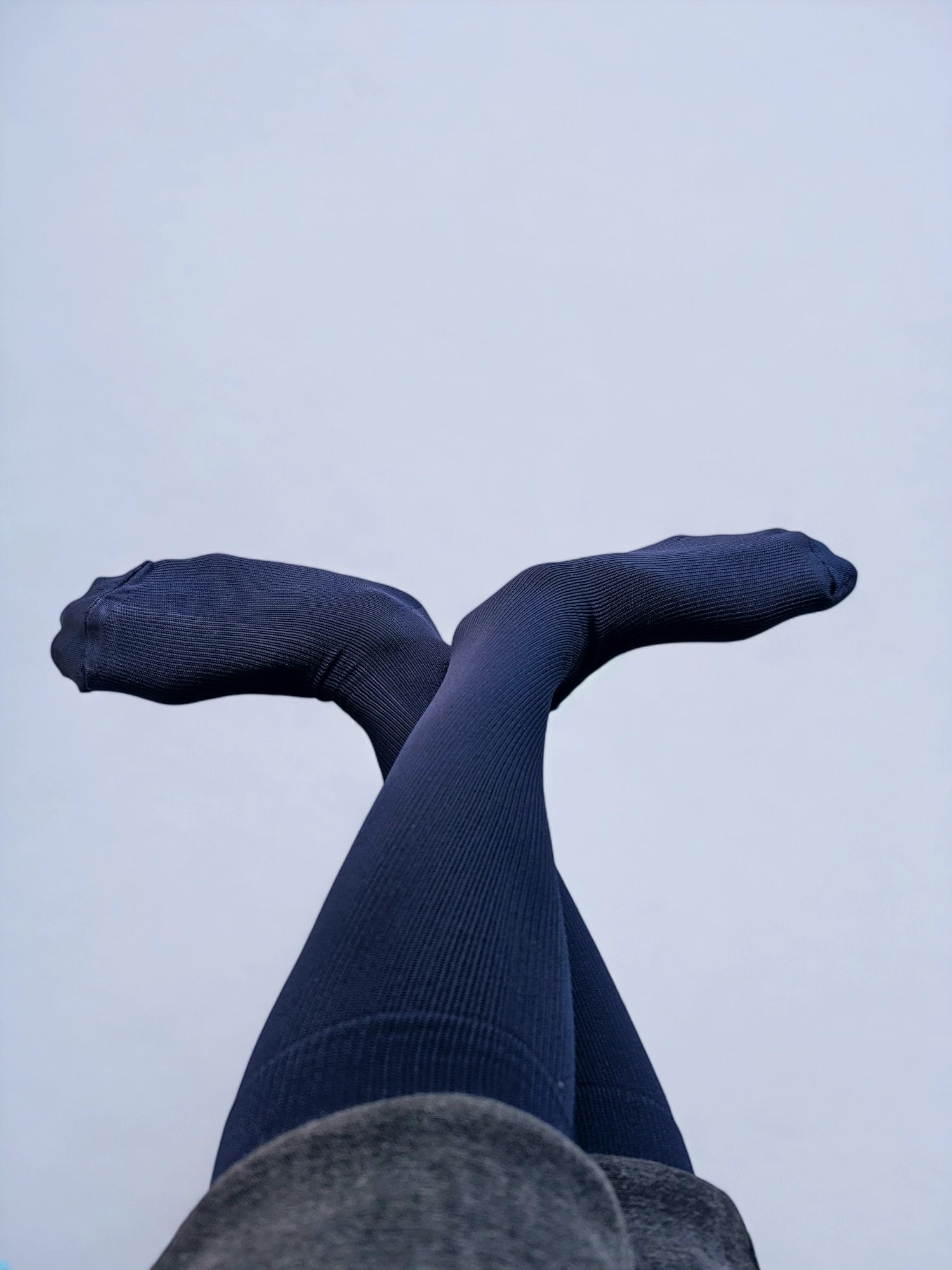 Two legs wearing navy blue graduated compression socks crossed over each other 