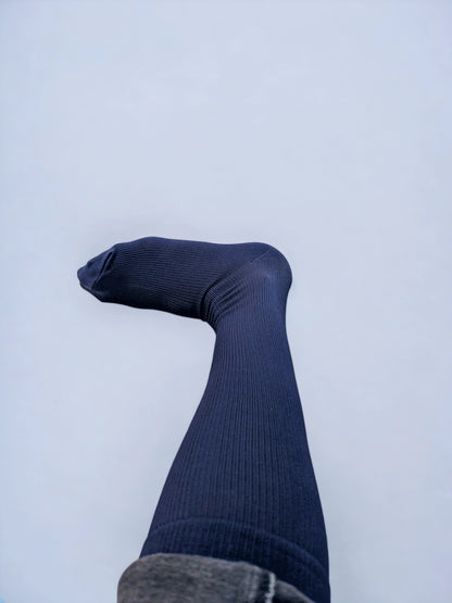 A leg wearing navy blue graduated compression socks turned sideways.