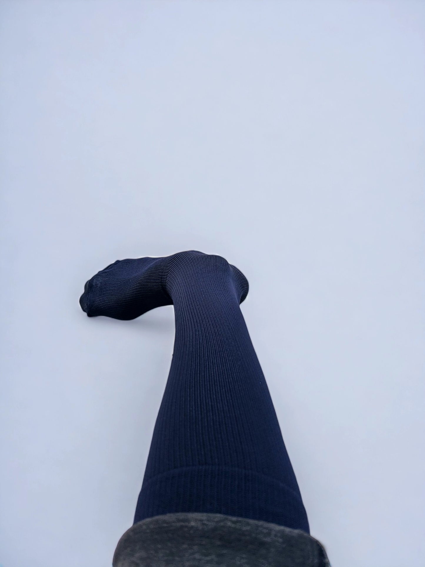 A leg wearing navy blue graduated compression socks turned sideways.