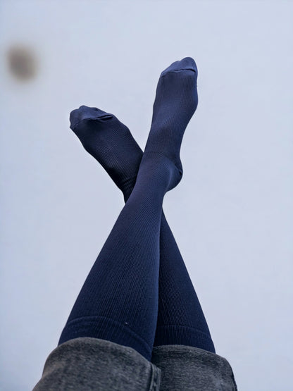 Two legs wearing navy blue graduated compression socks crossed over each other 