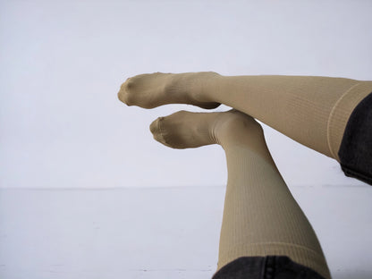 A pair of legs wearing skin-colored compression socks