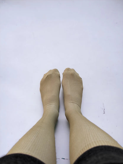 A pair of legs wearing skin-colored compression socks