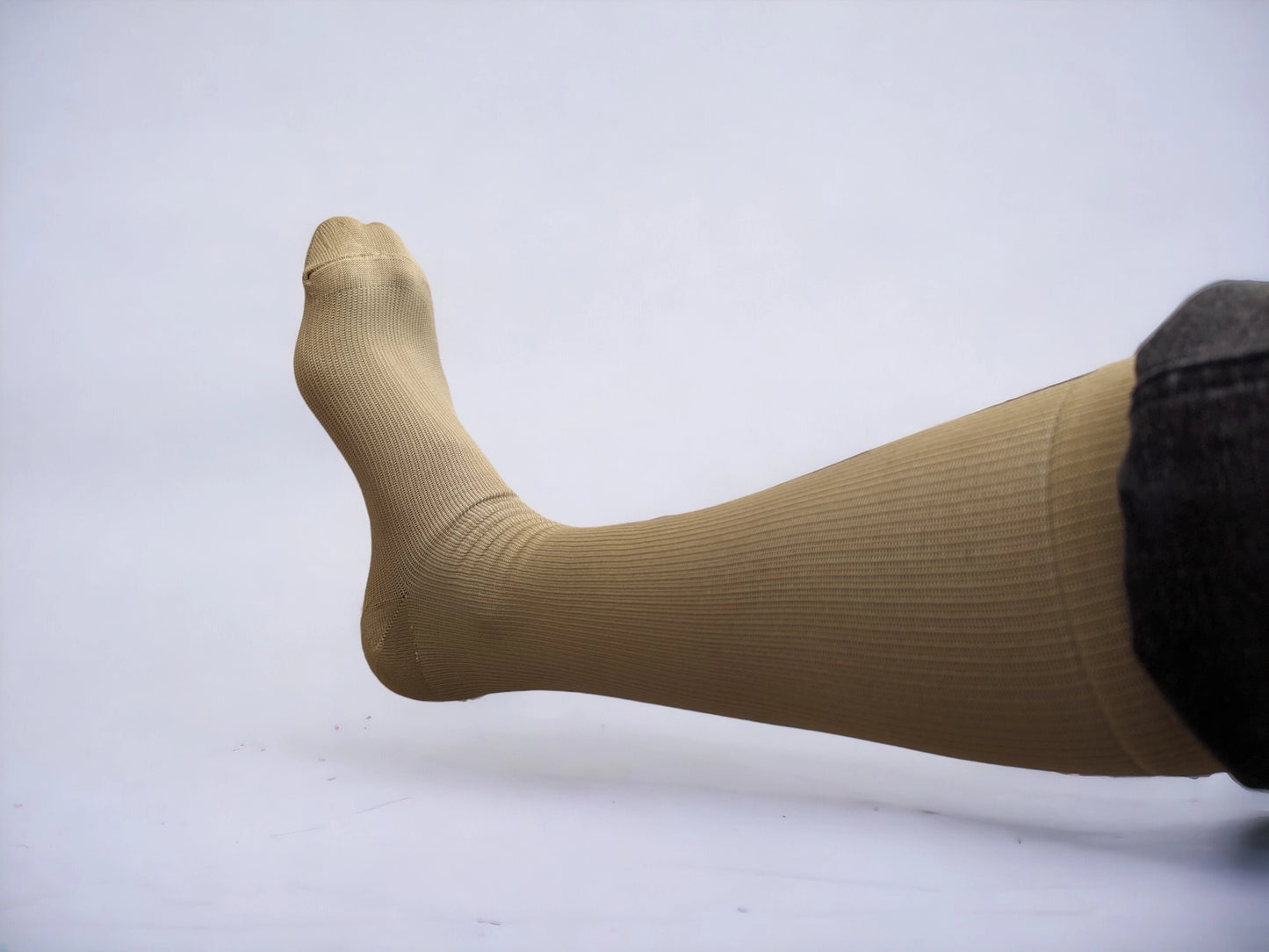 A leg wearing skin-colored compression socks pointing to left