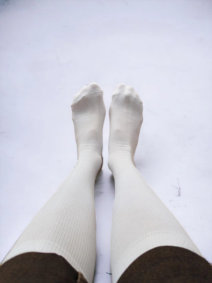 A pair of legs wearing white compression socks raised upward.