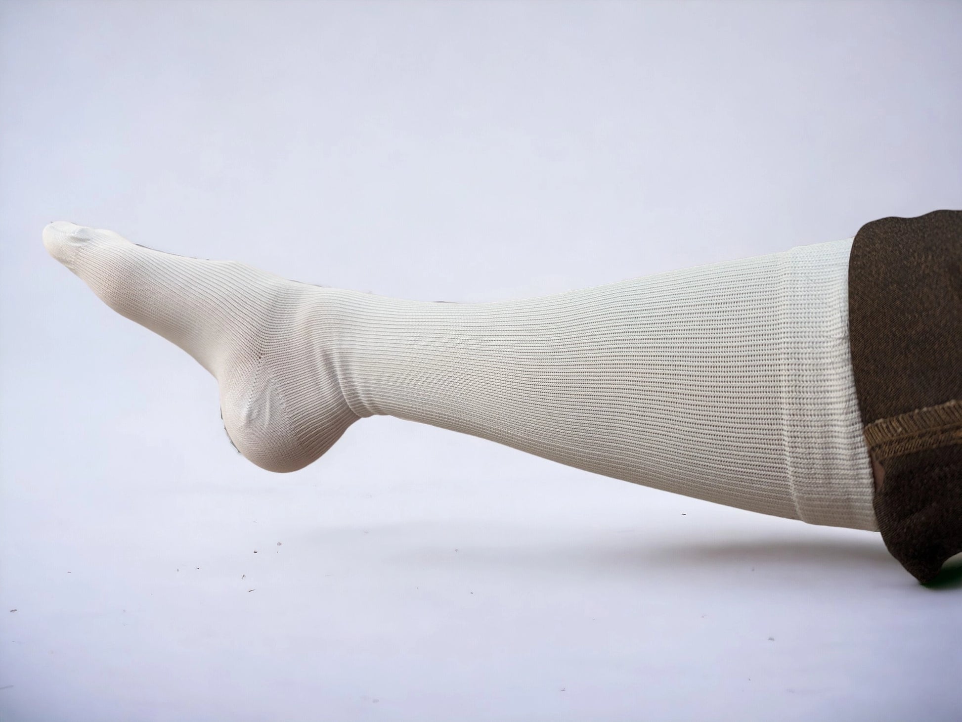 A leg wearing skin-colored compression socks pointing to left