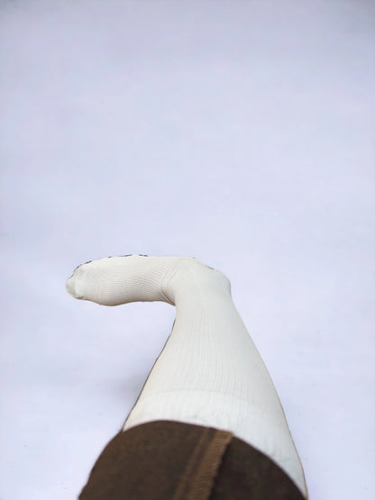 A leg wearing skin-colored compression socks raised upward 