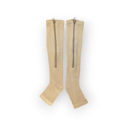 A pair of skin colored zippered knee-high compression socks